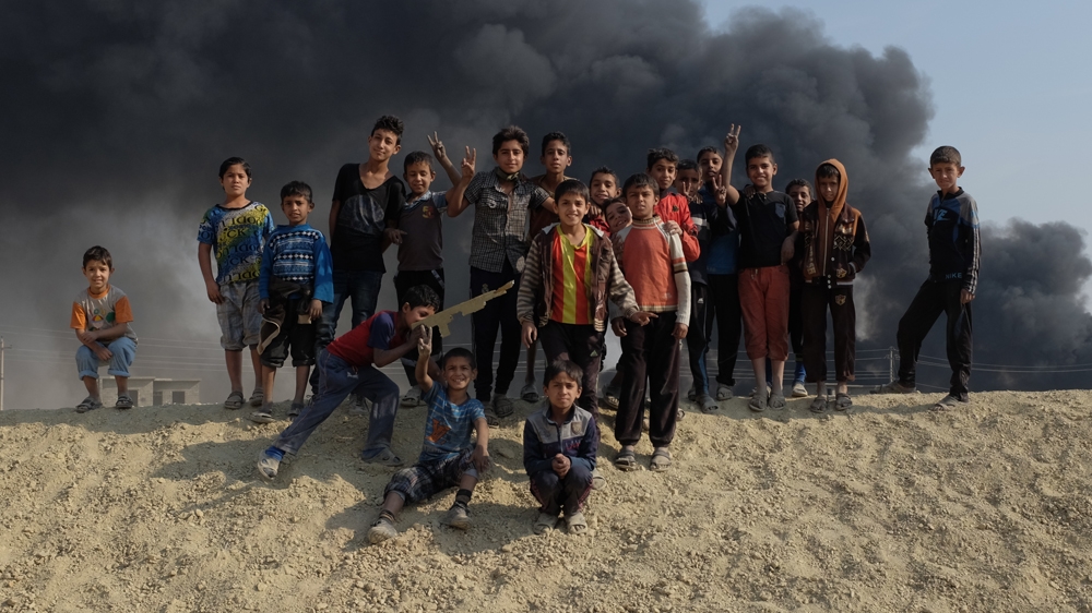 Children playing around a oil wells on fire in Qayyara, Iraq